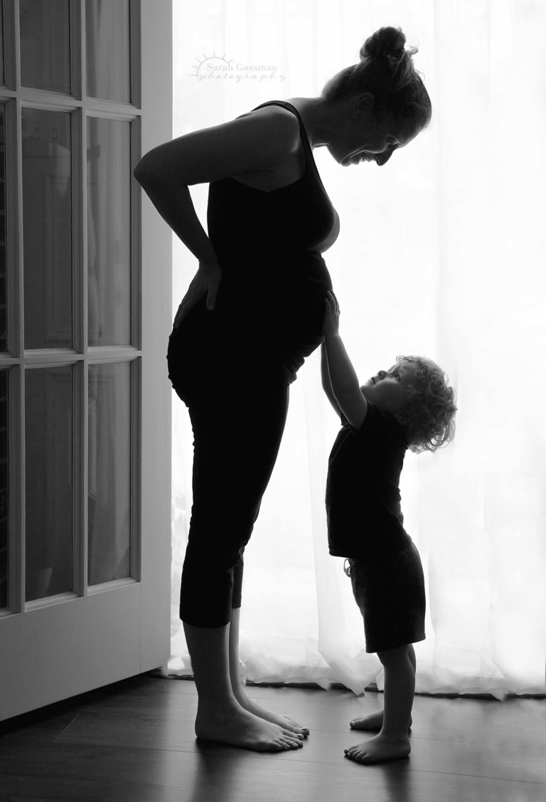 black and white silhouette of two year old son with pregnant mother, sweet baby bump moment with big brother, cypress maternity photographer