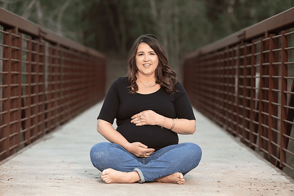 mama to be in jeans and black top on bridge at outdoor maternity photo session in Houston Texas, Houston maternity photographer