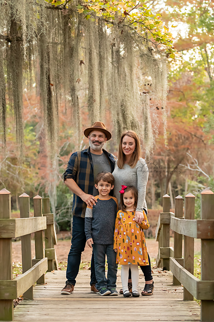 family of four in fall colors on bridge surrounded by mossy trees
