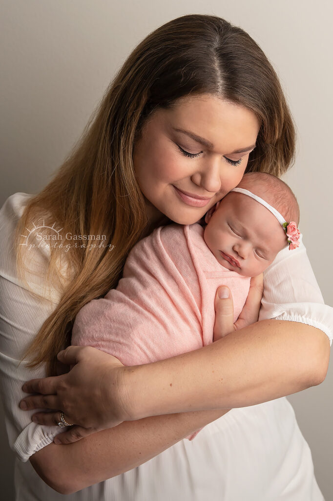 mom holds first bay girl and shows so much love at their Katy in-home newborn photoshoot with Houston newborn photographer