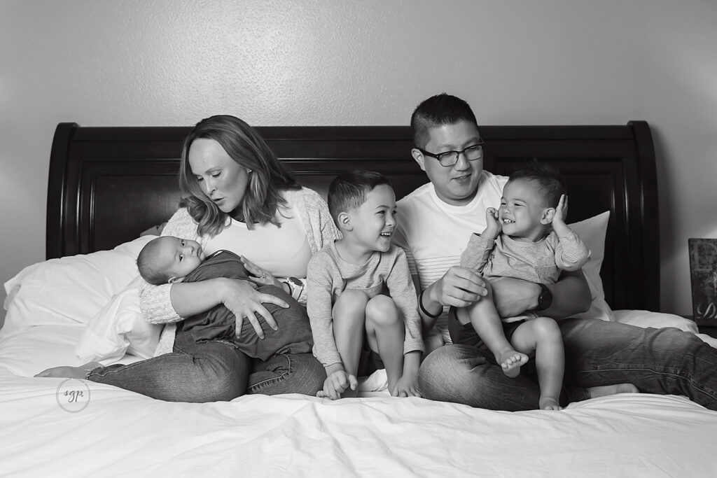 black and white family photo on bed at in-home newborn photography session Cypress, Texas