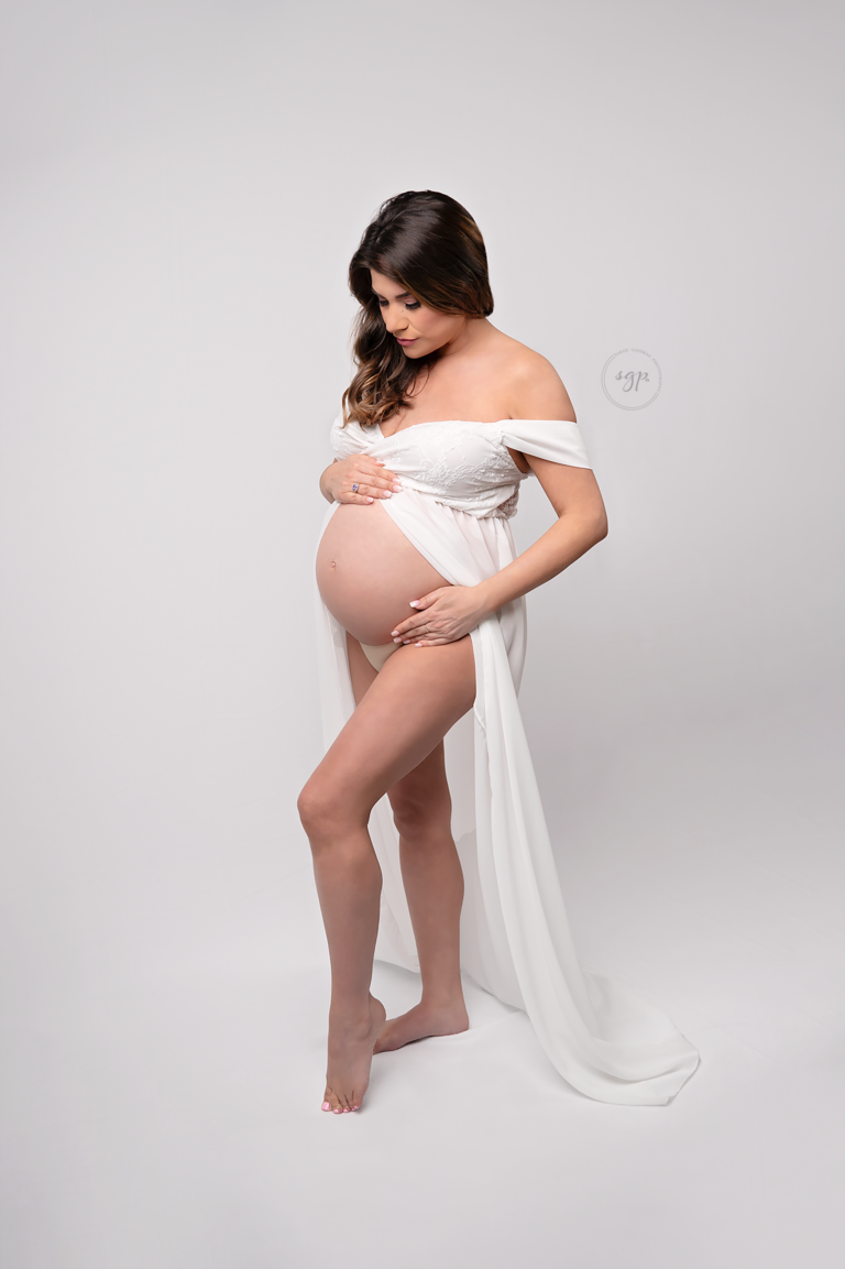 Expecting mother shows off her baby bump wearing an open front shear white maternity dress at her Houston maternity photo session