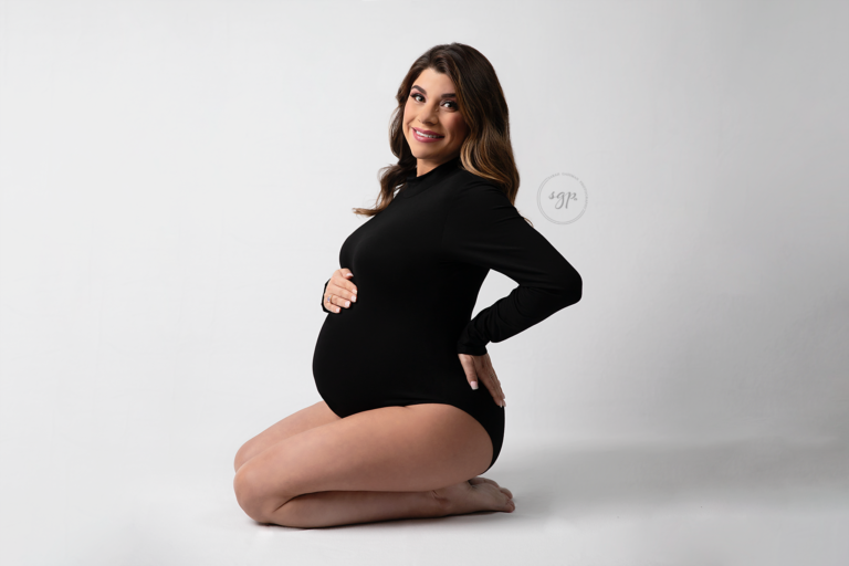 pregnant mama to be in black bodysuit showing off baby bump at in-home maternity photoshoot in Houston, TX. Houston maternity photographer