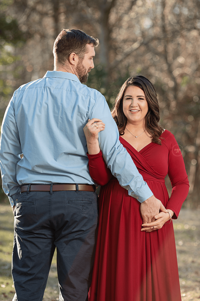 parents to be at outdoor maternity photo session, mom holds dad arm while he looks lovingly at her in Houston, Texas. Houston maternity photographer