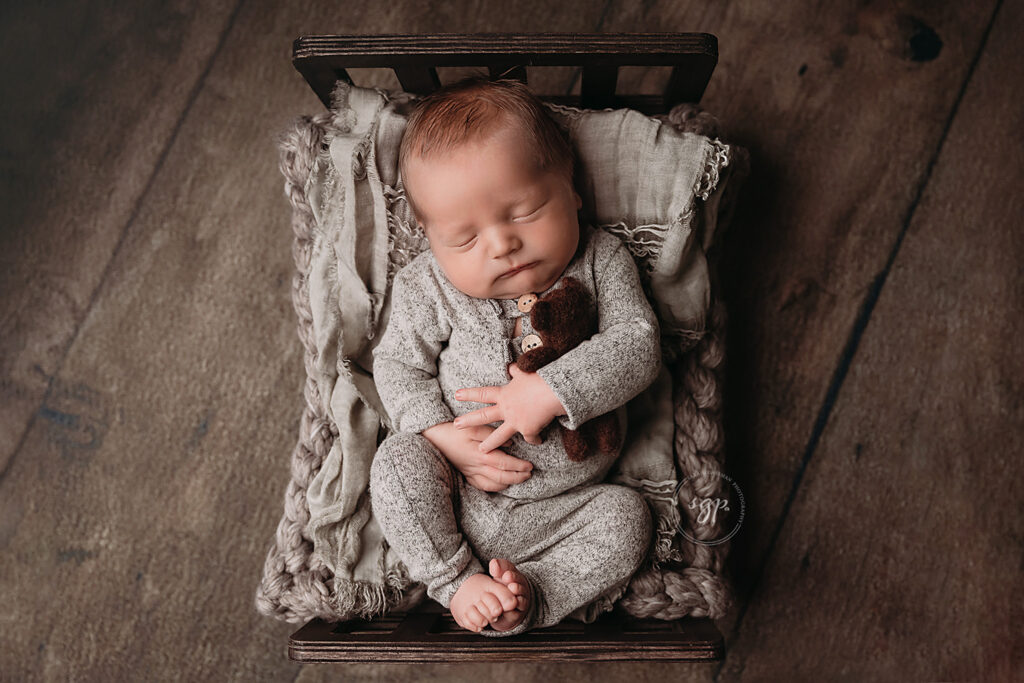 little baby hold tiny teddy while sleeping on baby bed as Houston newborn photo session, in-home newborn photos Houston, Houston newborn photographer