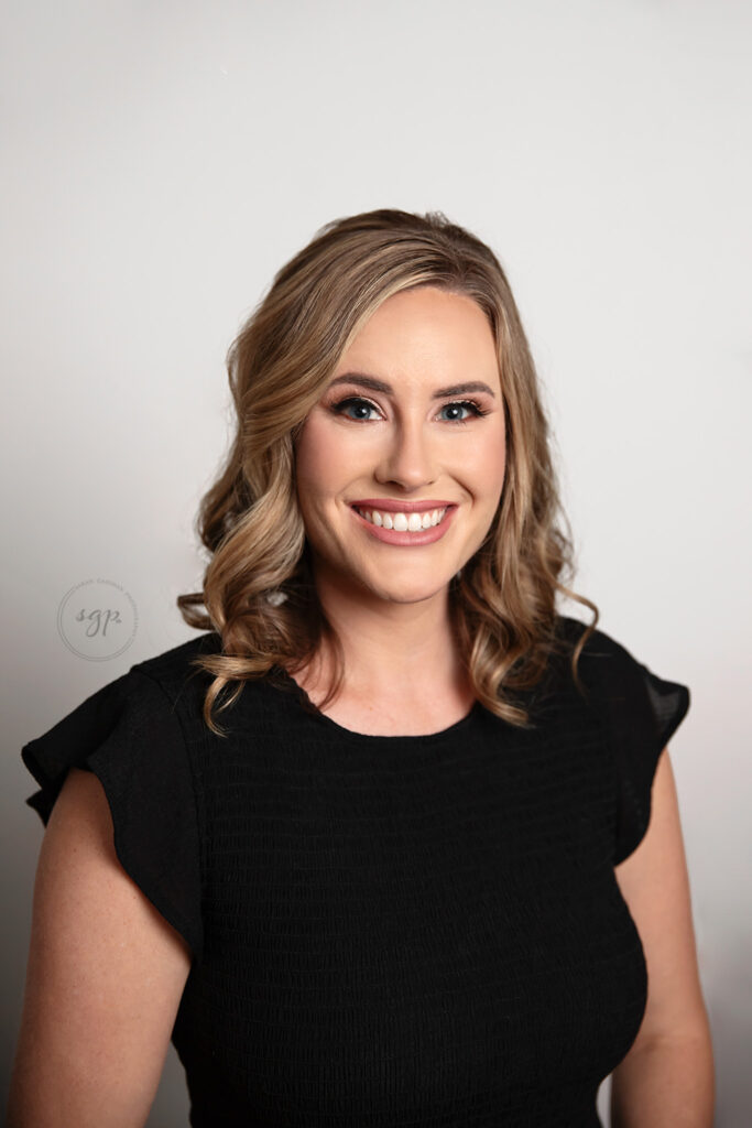 headshot of woman in black dress with light gray background