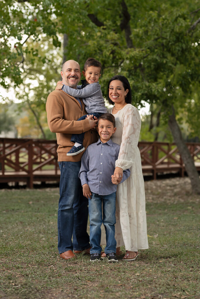 family of four in blue, cream, and camel at outdoor family photo session Houston Texas
