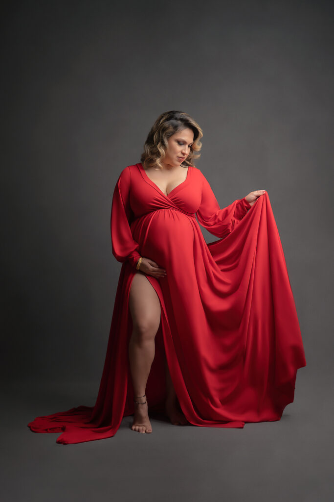 fine art maternity photo of mama to be in long red, flowy dress