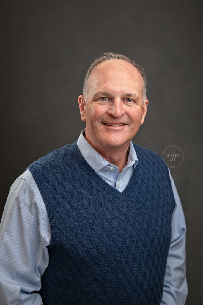 corporate headshot with male in navy sweater vest