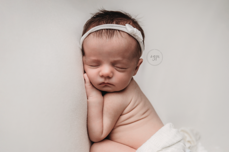 baby girl sleeping soundly wrapped in white with bay rolls showing