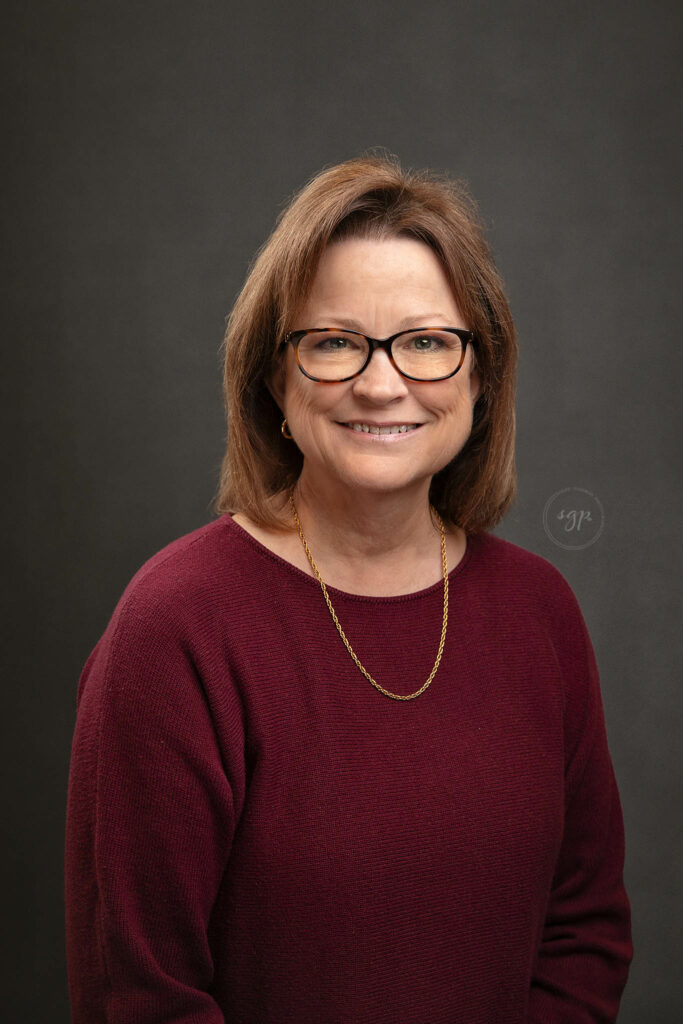 corporate of heashot with woman in glasses and burgundy colored sweater