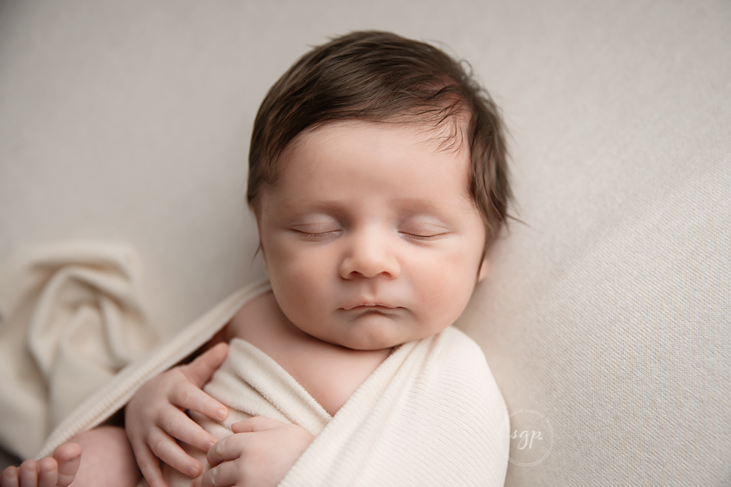 sleeping baby boy wrapped in soft beige at in-home newborn photo session