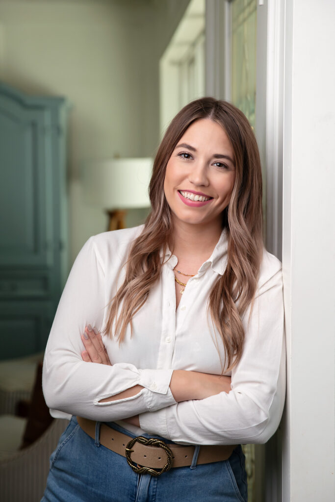modern headshot of woman leaning on wall wearing a white shirt and jeans